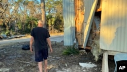 Dave Beamer walks past the partially destroyed trailer he's been living in, Sept. 29, 2024, in Steinhatchee, Florida, after Hurricane Helene washed his home into a marsh.