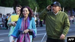 El presidente de Nicaragua, Daniel Ortega, acompañado por su esposa y vicepresidenta Rosario Murillo, saludando a su llegada a un desfile militar para conmemorar el 44º aniversario del Ejército.