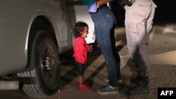 FILE - A 2-year-old Honduran asylum seeker cries as her mother is searched and detained near the U.S.-Mexico border in McAllen, Texas, June 12, 2018. Getty Images photographer John Moore won the 2019 World Press Photo of the Year award for this photo.