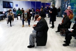 People wait at the reception hall of a COVID-19 vaccination mega center in Athens, Feb. 15, 2021.
