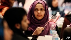 FILE - A young woman waves an American flag along with others at the beginning of a Muslim conference against terror and hate at the Curtis Culwell Center, Jan. 17, 2015, in Garland, Texas.