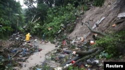 Warga membersihkan tanah longsor di jalan seusai dihantam Badai Tropis Julia disertai angin dan hujan, di San Salvador, El Salvador, 10 Oktober 2022. REUTERS/Jose Cabezas