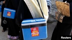 FILE - Polio vaccinators carry boxes of polio vaccine drops as they head to the areas they have been appointed to administer the vaccine, in Karachi, Oct. 21, 2014.