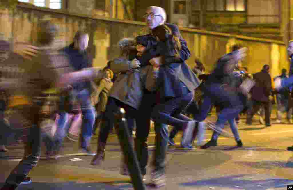 A man carries two children after panic broke out among mourners who paid their respects at the attack sites at restaurant Le Petit Cambodge (Little Cambodia) and the Carillon Hotel in Paris, Nov. 15, 2015.