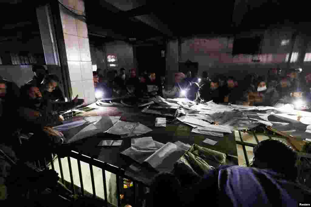 People search through papers as they join members of the Syrian civil defense group, known as the White Helmets, to search for prisoners underground at Sednaya prison, in Sednaya, Dec. 9, 2024.