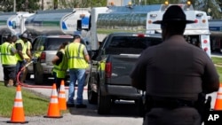 A Florida Highway Patrol officer watches as fuel depot workers distribute gas to residents, Oct. 12, 2024, in Plant City.