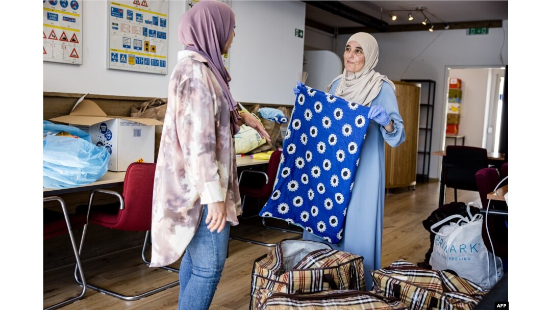 FILE - A local resident (L) donates items for the victims of the earthquake in Morocco at a collection point in Eindhoven, on September 11, 2023.