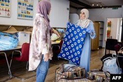 FILE - A local resident (L) donates items for the victims of the earthquake in Morocco at a collection point in Eindhoven, on September 11, 2023.