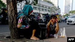 Seorang anak bersama neneknya beristirahat di jalur pejalan kaki di Jakarta, 10 Oktober 2019. Maraknya makanan murah dan mengenyangkan, tapi minim gizi mengakibatkan jutaan anak mengalami masalah kesehatan. (Foto: AFP)