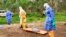 In this photo taken on Friday, June 19, 2015, the wrapped remains of a new born child suspected of contracting the Ebola virus, lays on a stretcher as health workers, dressed in Ebola protective gear, move the body for burial in Dubreka, Guinea. 