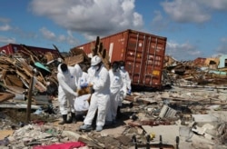 A Bahamas coroners team carries a body out of The Mudd neighborhood in the Marsh Harbor area of Abaco Island in the Bahamas in the aftermath of Hurricane Dorian, Sept. 9, 2019.