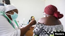 FILE - A medical worker injects the AstraZeneca's COVID-19 vaccine into a woman at the National Hospital in Abuja, Nigeria, March 31, 2021. 