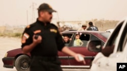 An Iraqi counterterror officer talks to people in a convoy of families fleeing Islamic State-held Hit, Iraq, at a checkpoint on the western edge of Ramadi, Iraq, March 20, 2016.