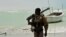 A Somali, part armed militia, part pirate, carries his high-caliber weapon on a beach in the central Somali town of Hobyo on August 20, 2010.