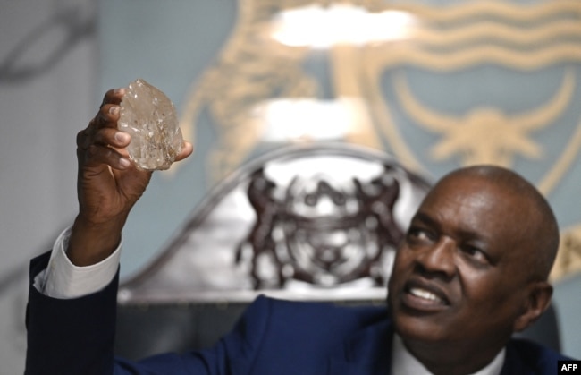 Botswana's President Mokgweetsi Masisi holds a large diamond discovered in Botswana at his office in Gaborone on August 22, 2024. (Photo by Monirul BHUIYAN / AFP)