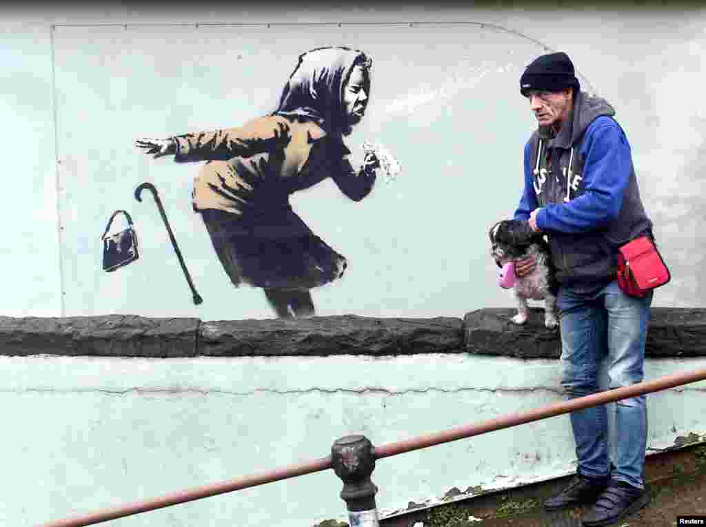 A man stands near a new street artwork entitled &quot;Aachoo!!&quot; by Banksy in Totterdown, Bristol, Britain.
