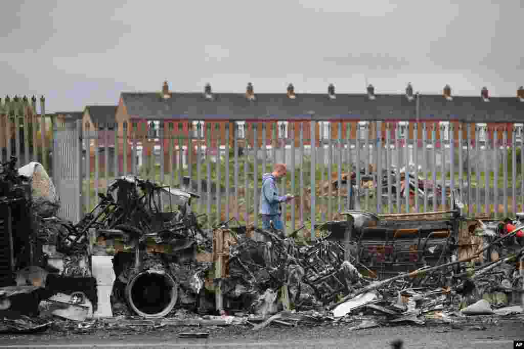 A man walks past a burnt out bus on the Shankill road in West Belfast, Northern Ireland. Authorities sought to restore calm after Protestant and Catholic youths in Belfast hurled bricks, fireworks and gasoline bombs at police and each other.&#160;