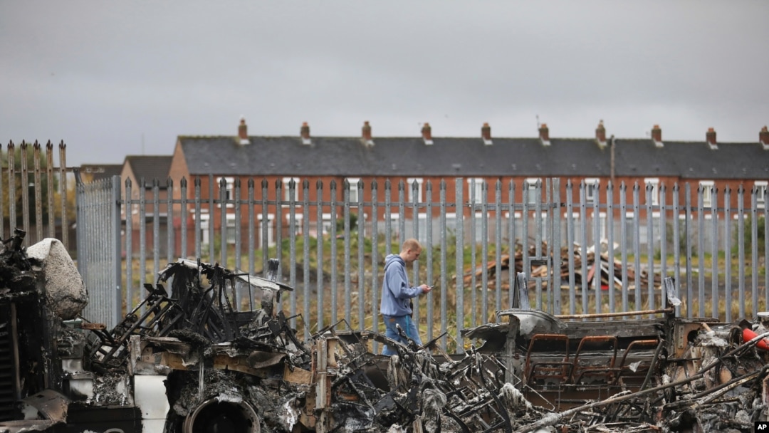 A man walks past a burnt out bus on the Shankill road in West Belfast, Northern Ireland, April 8, 2021, after another night of violence in Loyalist areas that has now spread to interface areas of the peace divide.