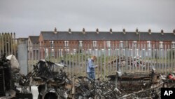 A man walks past a burnt out bus on the Shankill road in West Belfast, Northern Ireland, April 8, 2021, after another night of violence in Loyalist areas that has now spread to interface areas of the peace divide.