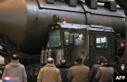 Pemimpin Korea Utara Kim Jong Un (tengah atas) menaiki peluncur transportasi saat ia memeriksa pabrik produksi kendaraan militer penting bersama putrinya Ju Ae (jauh kanan) di lokasi yang dirahasiakan di Korea Utara. (Foto: KCNA VIA KNS/AFP)