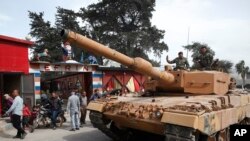 Turkish soldiers atop a tank patrol the northwestern city of Afrin, Syria, during a Turkish government-organized media tour into northern Syria, March 24, 2018.