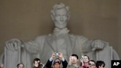 Para wisatawan berfoto di depan patung Presiden AS Abraham Lincoln, yang terletak di dalam gedung Lincoln Memorial di Washington DC (foto: dok).