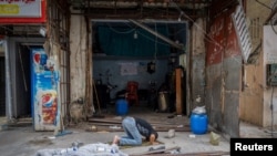 A man prays outside his shop damaged in an Israeli strike, after the ceasefire between Israel and Hezbollah, in Tyre, southern Lebanon. 