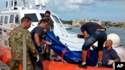 The body of a drowned migrant is being unloaded from a Coast Guard boat in the port of Lampedusa, Italy, Oct. 3, 2013. 