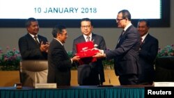 FILE - Civil Aviation Malaysia's Director-General Azharuddin Abdul Rahman and Ocean Infinity's CEO Oliver Plunkett exchange documents during the MH370 search operations signing ceremony between Malaysia's government and Ocean Infinity, in Putrajaya, Malaysia, Jan. 10, 2018.