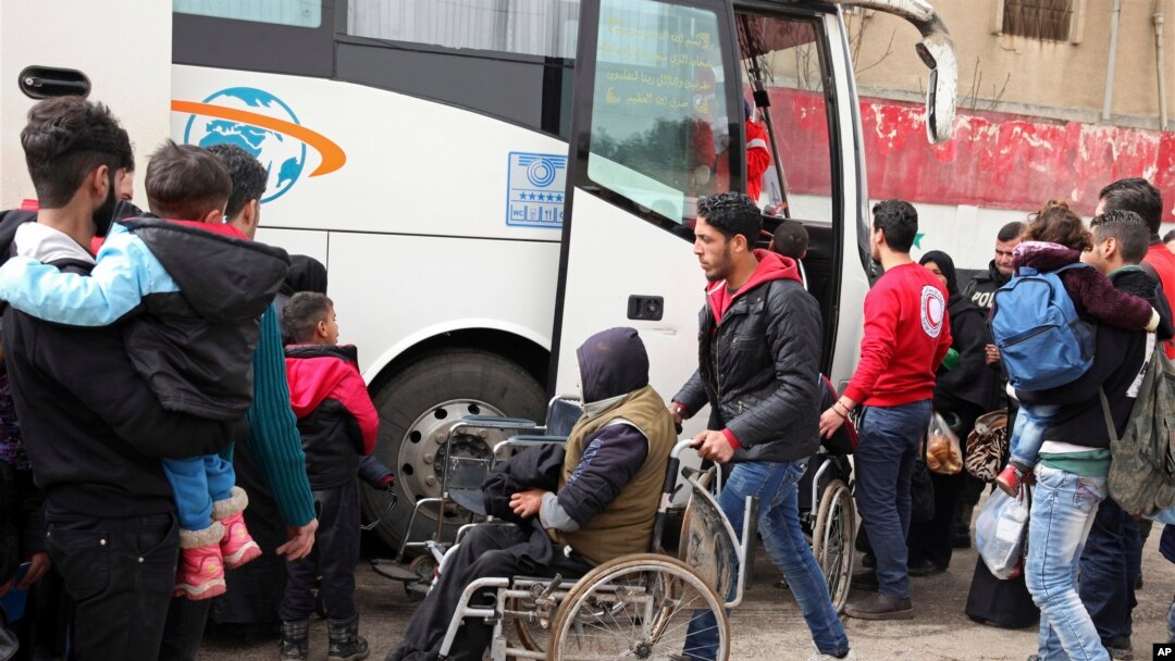 Anggota Palang Merah Suriah membantu keberangkatan para pejuang oposisi dan keluarga mereka saat mereka bersiap untuk meninggalkan lingkungan al-Waer, menuju sebuah kota di perbatasan Turki, di Homs, Suriah, Sabtu, 18 Maret 2017.(Foto: dok).
