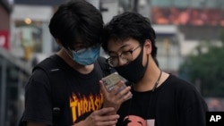 Men look at a smartphone in Beijing on Monday, July 5, 2021. Days after China's largest ride-hailing app Didi Global Inc. went public in New York as the biggest Chinese IPO in the U.S. since Alibaba's 2014 listing, Chinese regulators clamped down on…