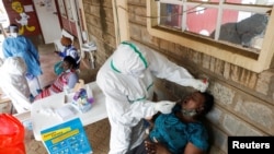 Health workers collect swab samples during free mass testing for the COVID-19 in Kibera slums of Nairobi, Kenya, Oct. 17, 2020. 