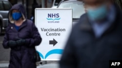 FILE - Members of the public pass an NHS Scotland vaccination center set up at the Edinburgh International Conference Centre (EICC) in Edinburgh, Feb. 1, 2021. 