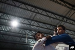 In this May 27, 2016 photo, Popole Misenga, a refugee from the Democratic Republic of Congo, left, practices judo in hopes of making the cut for an Olympic team of refugee athletes, at the Reacao Institute in Rio de Janeiro, Brazil.