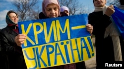 FILE - An ethnic Tatar women attends a rally denouncing a referendum which Moscow used to legitimize its annexation of Ukraine's Crimea, in Simferopol, March 14, 2014. The sign reads "Crimea is Ukraine.