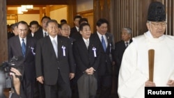Japanese lawmakers, including cabinet ministers, are led by a Shinto priest as they visit the Yasukuni Shrine for the war dead in Tokyo, October 18, 2012.