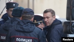 Russian opposition leader Alexei Navalny is escorted upon his arrival for a hearing after being detained at the protest against corruption, at the Tverskoi court in Moscow, Russia, March 27, 2017. 