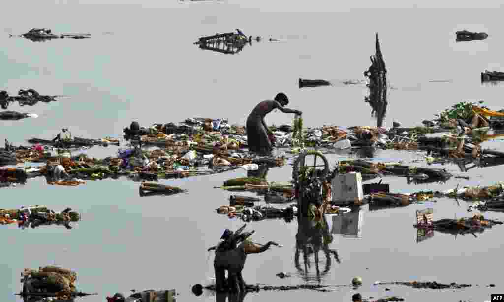 Indian scavengers look for coins and other valuable items amongst the religious offerings from devotees and leftover wooden frames of Lord Ganesh idols which are piled up in the Yamuna River in New Delhi.