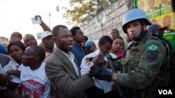 Haitianos a las puertas de las mesas electorales esperan para votar mientras un agente de la ONU intenta organizarlos.