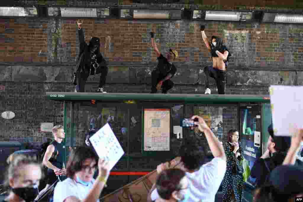 Demonstrators stand on top of a bus shelter they march near the US Embassy in central London on May 31, 2020, to protest the death of George Floyd.