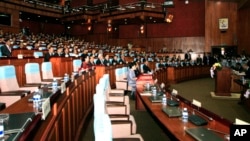 FILE - Prime Minister Hun Sen, front row center, and lawmakers from his ruling Cambodian People's Party sit near empty seats held by opposition lawmakers, inside the session hall of the National Assembly, in Phnom Penh, Cambodia, Tuesday, Sept. 24, 2013.