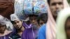 FILE - Migrants from Bangladesh who were found at sea carry their belongings as they cross the Myanmar-Bangladesh friendship bridge to return to Bangladesh, in Taungpyo, northern Rakhine state June 8, 2015.