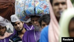 FILE - Migrants from Bangladesh who were found at sea carry their belongings as they cross the Myanmar-Bangladesh friendship bridge to return to Bangladesh, in Taungpyo, northern Rakhine state June 8, 2015.