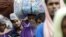 FILE - Migrants from Bangladesh who were found at sea carry their belongings as they cross the Myanmar-Bangladesh friendship bridge to return to Bangladesh, in Taungpyo, northern Rakhine state June 8, 2015.