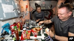 FILE - NASA astronauts Suni Williams and Butch Wilmore make pizza aboard the International Space Station's galley located inside the Unity module, Sept. 9, 2024. (NASA via AP)