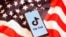 Tik Tok logo is displayed on a smartphone on the U.S. flag in this illustration 