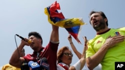 FILE - Chacao Mayor Ramon Muchacho, right, and Venezuelan singer Jesus Alberto Miranda, known as Chino, sing the national anthem during an anti-government protest in Caracas, Venezuela. Venezuela's high court ordered the removal and arrest of Muchacho Aug. 8, 2017, for not following an order to remove barricades set up in his district of Caracas. 