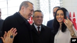 Turkey's President Recep Tayyip Erdogan, left, poses for a selfie photo with Imane Elbani, right, at his palace before addressing a group of farmers, in Ankara, Turkey, Monday, Nov. 14, 2016. 