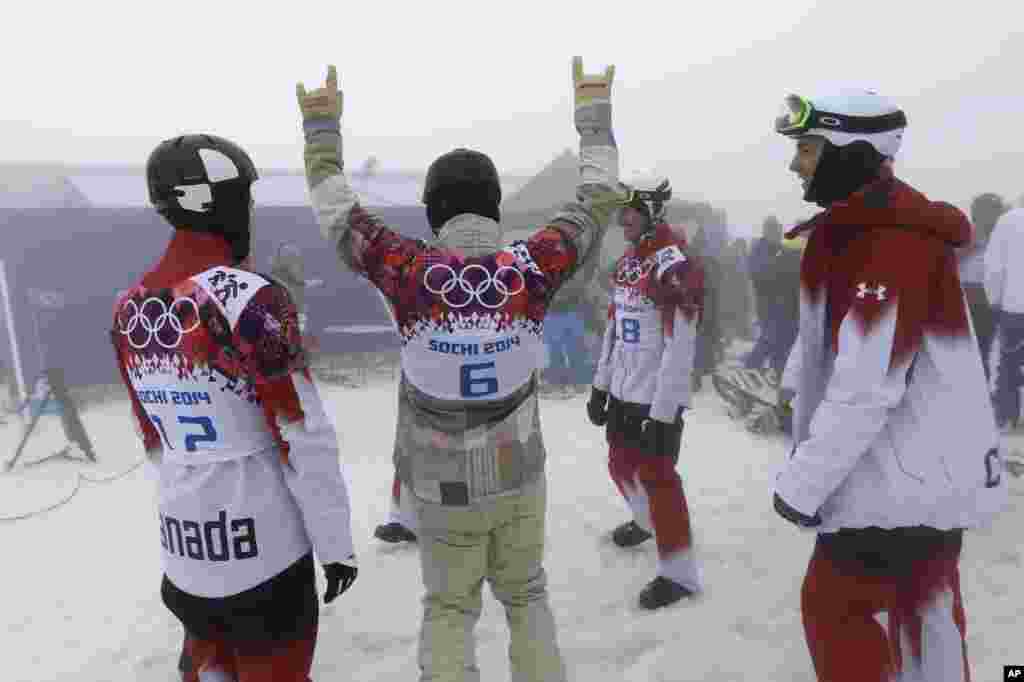 The United States' Nick Baumgartner jokes with Canadian athletes as they wait for the start of men's snowboard cross competition that was later cancelled due to fog at the Rosa Khutor Extreme Park, Feb. 17, 2014.