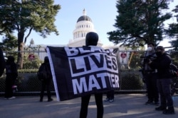 A demonstrator holds a "Black Lives Matter" flag during a protest at the state Capitol in Sacramento, Calif., Jan. 20, 2021.